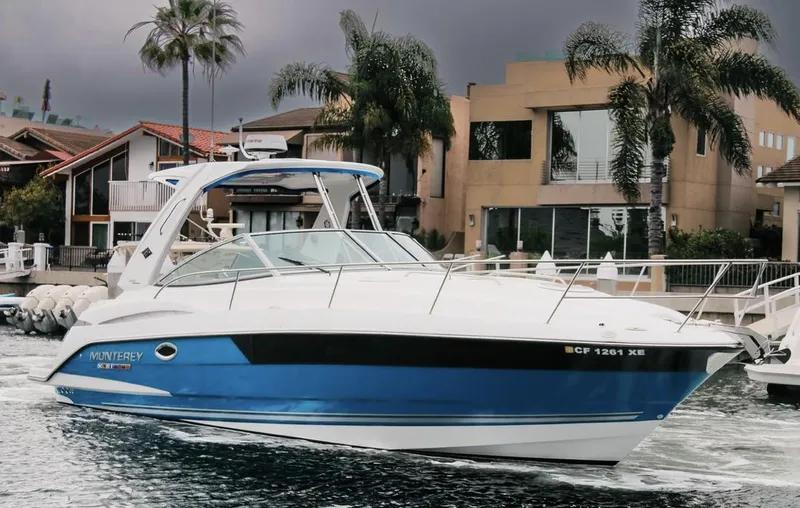 Slide: The Image of 2020 Monterey 355 Sport Yacht cruising near waterfront homes, featuring sleek blue and white design. - 0