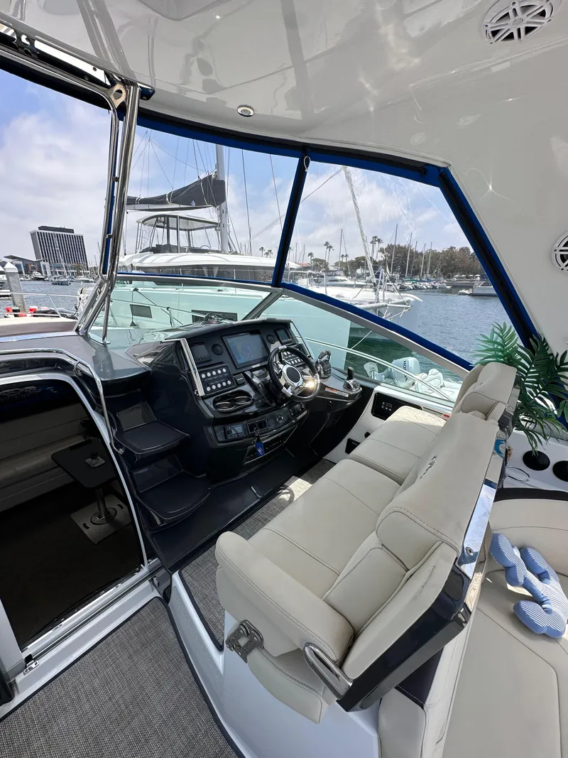 Slide: The Image of 2020 Monterey 355 Sport Yacht cockpit with modern controls, plush seating, and marina view. - 32