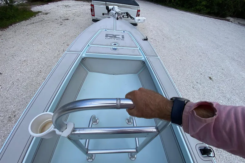 Slide: The Image of 2019 Cayo Boatworks 173 skiff, hand on rail, parked on gravel. - 36