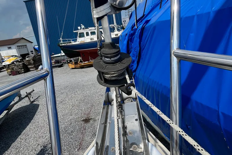 Slide: The Image of 1995 Hunter 29.5 sailboat with blue cover, docked in a marina. - 15