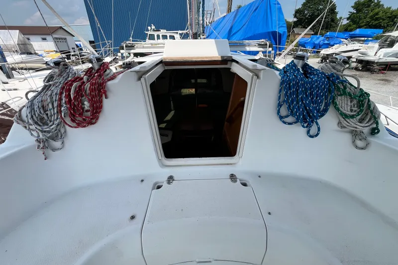 Slide: The Image of 1995 Hunter 29.5 sailboat cockpit with ropes, open hatch, and marina background. - 20