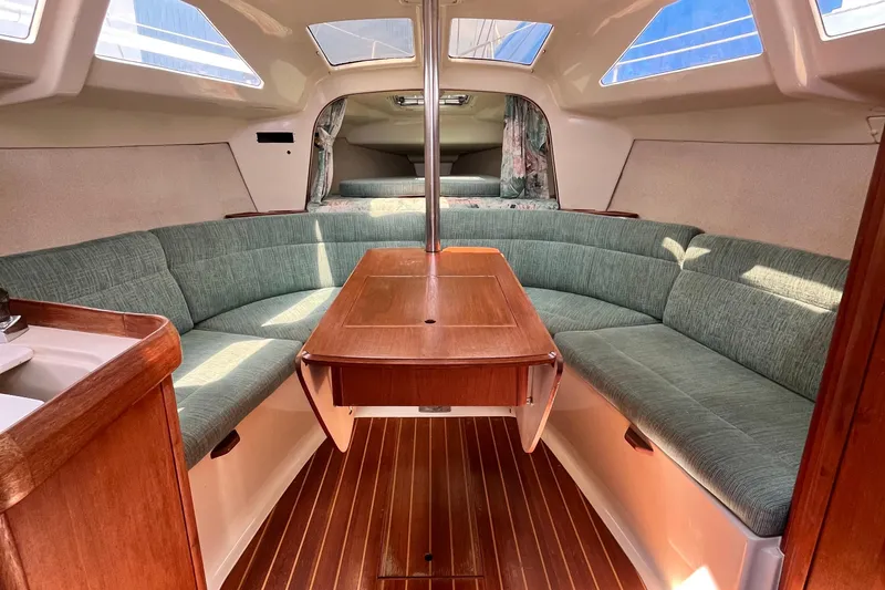 Slide: The Image of Interior of a 1995 Hunter 29.5 sailboat with green seating and wooden table. - 21