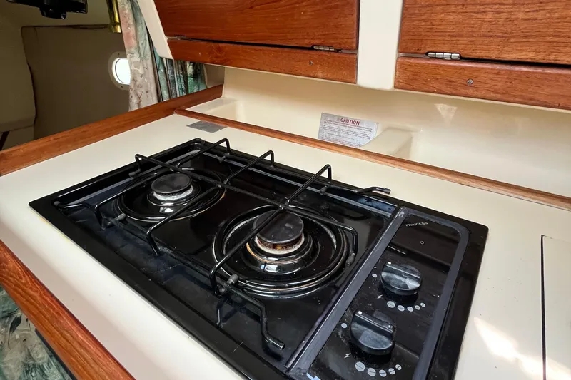 Slide: The Image of 1995 Hunter 29.5 yacht kitchen with two-burner stove and wooden cabinetry. - 26