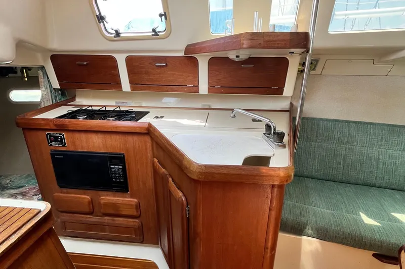 Slide: The Image of Interior of a 1995 Hunter 29.5 sailboat featuring a compact kitchen with stove and microwave. - 30