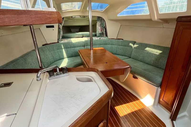 Slide: The Image of Interior of a 1995 Hunter 29.5 sailboat with green seating and wooden table. - 31