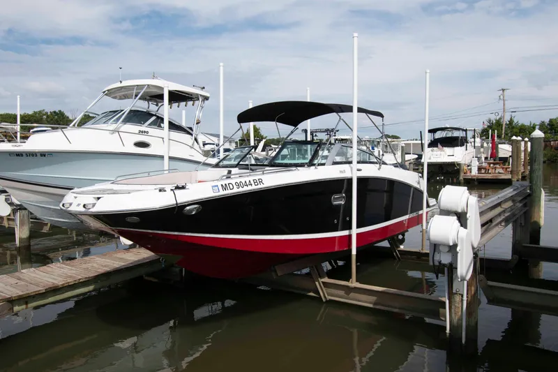 The Image of 2022 Four Winns HD8 boat docked at marina, black and red hull, sunny day. - 0