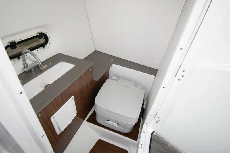Slide: The Image of 2022 Four Winns HD8 boat bathroom with sink and portable toilet. - 12