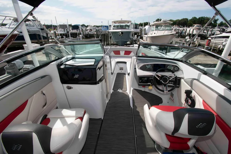 Slide: The Image of 2022 Four Winns HD8 boat interior with modern dashboard and seating at a marina. - 3