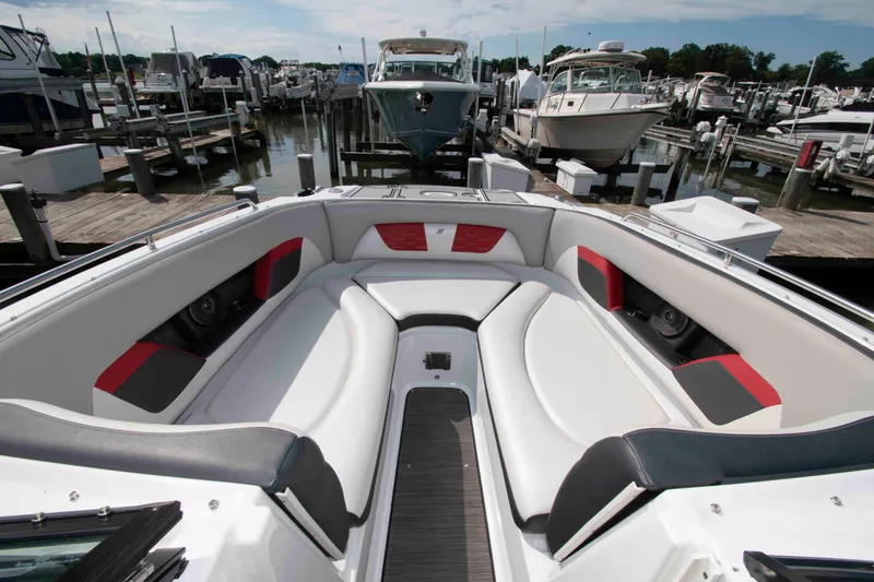 Slide: The Image of 2022 Four Winns HD8 boat interior with white and red seating at a marina. - 9
