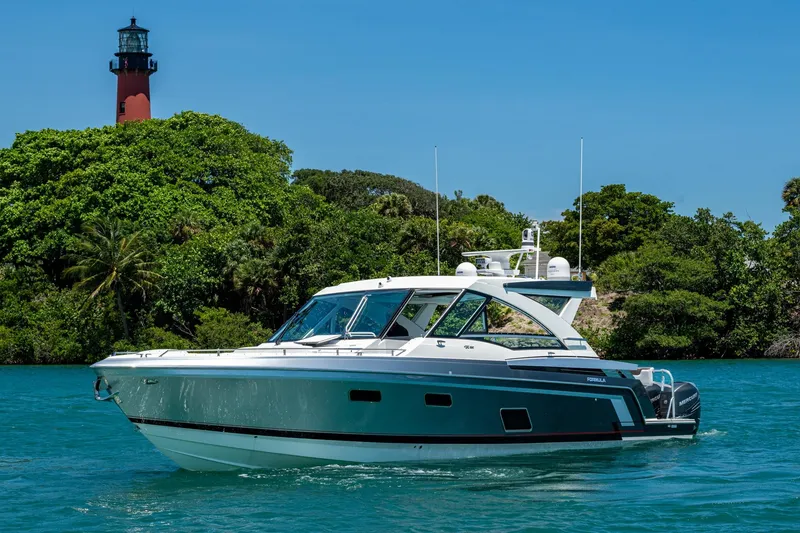 Slide: The Image of 2019 Formula 430 Super Sport Crossover yacht near lush greenery and lighthouse. - 2
