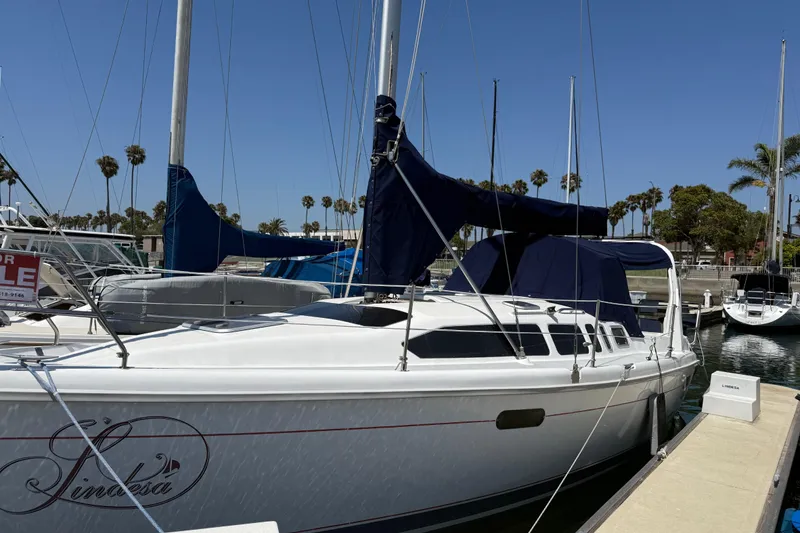 The Image of 1998 Hunter 34 sailboat docked, featuring blue covers and a "For Sale" sign. - 0
