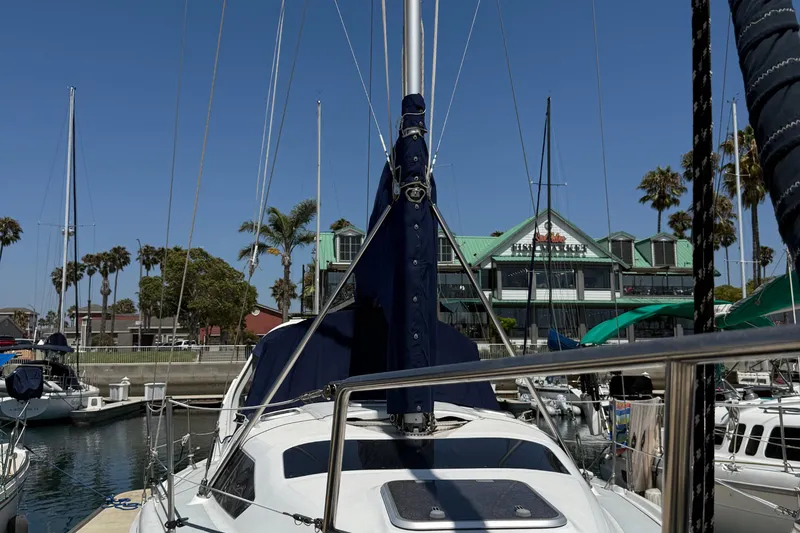 Slide: The Image of Hunter 34 sailboat docked at marina, 1998 model, with palm trees and building in background. - 1