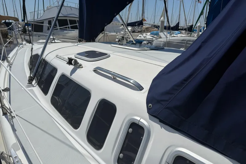 Slide: The Image of 1998 Hunter 34 sailboat deck with blue canvas cover in marina setting. - 2