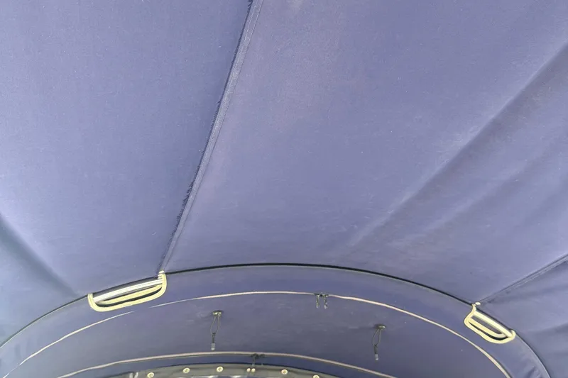Slide: The Image of Blue fabric canopy of a 1998 Hunter 34 sailboat, featuring metal hooks. - 7