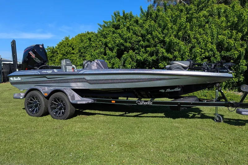 Slide: The Image of 2026 Bass Cat Cougar FTD SP boat on trailer, parked on grass with lush greenery background. - 2