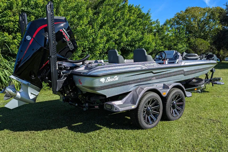 Slide: The Image of 2026 Bass Cat Cougar FTD SP boat on trailer, parked on grass with trees in background. - 4