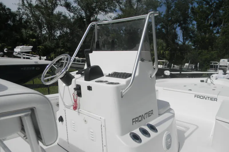 Slide: The Image of 2016 Frontier 2104 boat console with steering wheel and controls, surrounded by trees. - 3