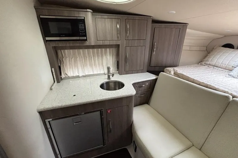 Slide: The Image of 2019 Regal 33 XO boat interior with kitchenette, sink, microwave, and cozy sleeping area. - 11