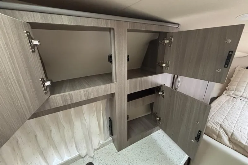 Slide: The Image of Open wooden cabinets inside a 2019 Regal 33 XO boat interior. - 18