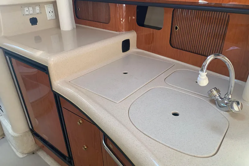 Slide: The Image of 2001 Sea Ray 340 Sundancer galley with sink, countertop, and wooden cabinetry. - 19