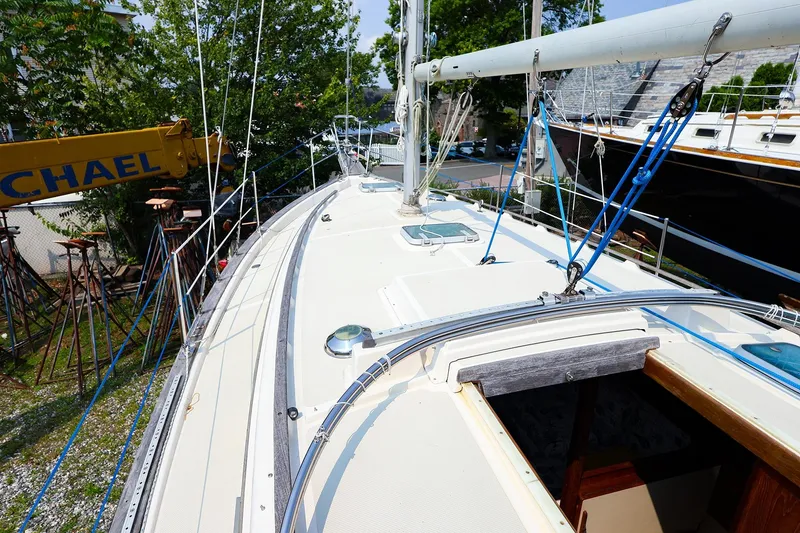 Slide: The Image of 1985 Island Packed 31 yacht deck with rigging and hatches, docked outdoors. - 2