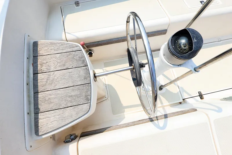 Slide: The Image of Steering wheel and compass of 1985 Island Packed 31 yacht, featuring wooden accents. - 9