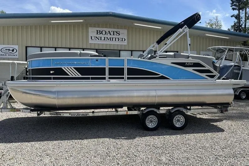 Slide: The Image of 2025 Bennington 22M pontoon boat on trailer at Boats Unlimited dealership. - 1