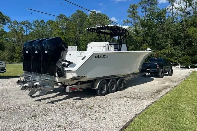 Slide: The Image of 2022 SeaHunter 33 Tournament boat on trailer, triple engines, parked outdoors. - 6