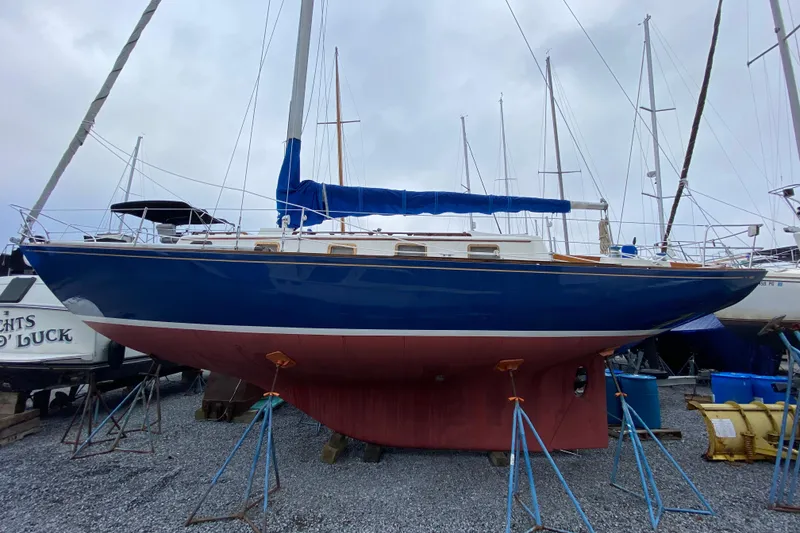Slide: The Image of 1972 Bristol 40 sailboat on stands, blue hull, red keel, marina setting. - 0