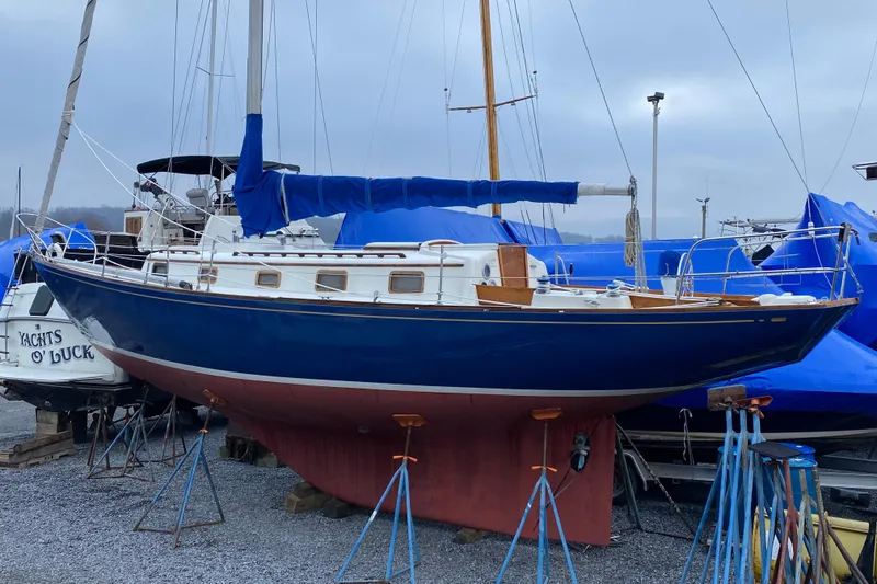 Slide: The Image of 1972 Bristol 40 sailboat on stands, blue hull, covered mast, in a boatyard. - 1