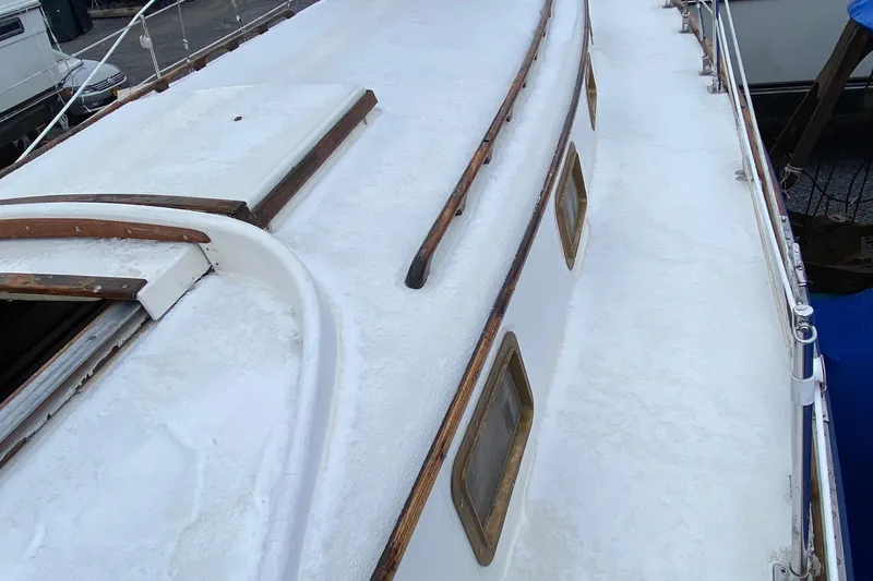 Slide: The Image of 1972 Bristol 40 sailboat deck covered in snow, showcasing wooden trim and portholes. - 19