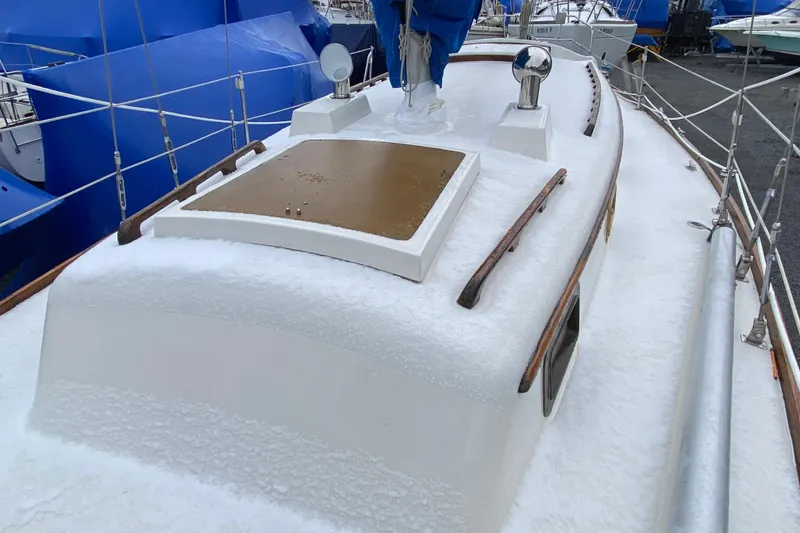 Slide: The Image of 1972 Bristol 40 sailboat deck covered in snow, docked with blue tarps in background. - 25