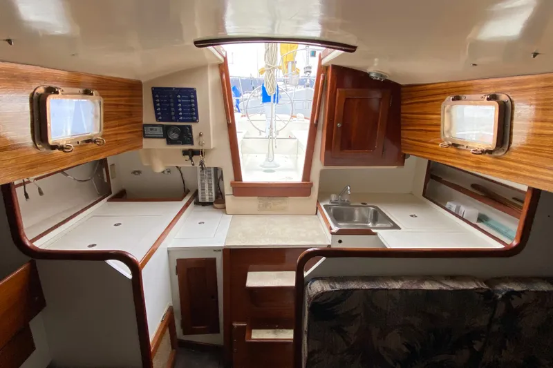 Slide: The Image of Interior of a 1972 Bristol 40 sailboat, featuring a compact kitchen and wooden cabinetry. - 34