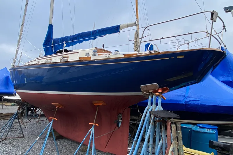 Slide: The Image of 1972 Bristol 40 sailboat on stands, blue hull, red keel, marina setting. - 8