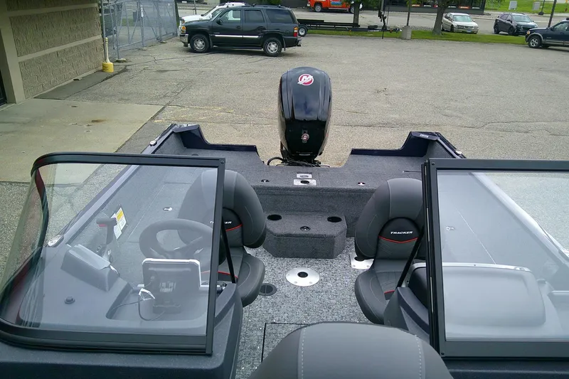 Slide: The Image of 2026 Tracker Pro Guide V-175 WT boat interior with seating and motor, parked outdoors. - 2