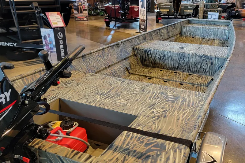 Slide: The Image of 2026 Tracker Grizzly 15 Jon boat with camouflage design displayed indoors. - 3