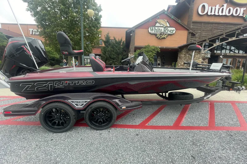 The Image of 2026 Nitro Z21 XL Pro boat on trailer, parked outside outdoor store, "We Take Trades" sign. - 0