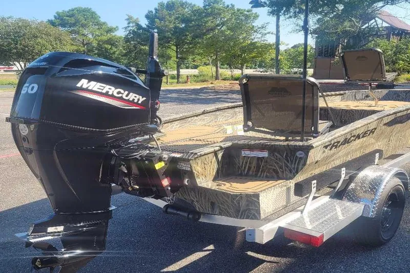 Slide: The Image of 2026 Tracker Grizzly 1650 T Prairie Wings Edition boat with Mercury engine, parked outdoors. - 3