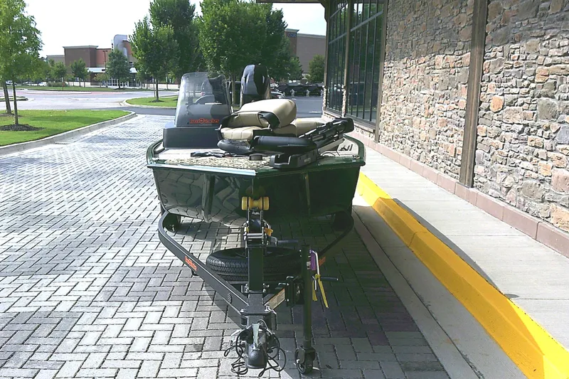 Slide: The Image of 2026 Tracker Bass Tracker Classic Limited boat parked on brick pavement near a stone building. - 2