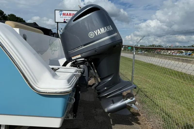 Slide: The Image of 2018 Sportsman Open 232 Center Console with Yamaha outboard motor, parked near a fence. - 3