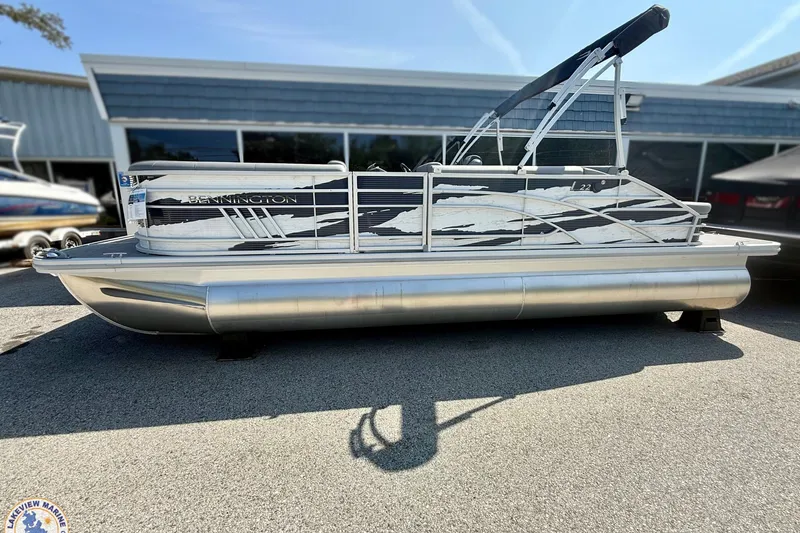 Slide: The Image of 2024 Bennington 22 LSB pontoon boat with sleek design, parked outdoors. - 12