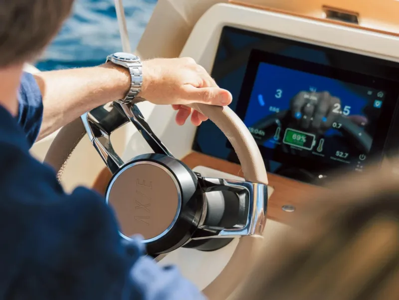 Slide: The Image of 2025 Axopar AX/E 22 T-Top steering wheel and dashboard display in use. - 4