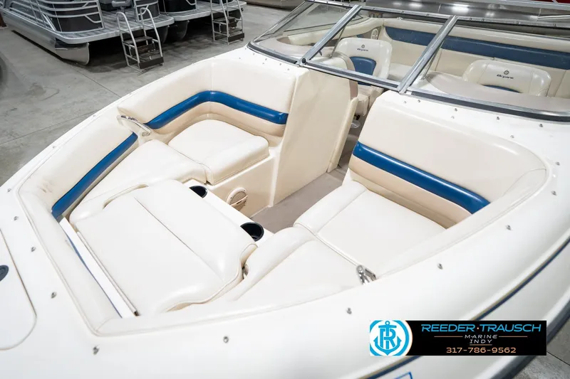Slide: The Image of 2000 Bryant 196 Limited boat interior with white and blue seating, showcased in a showroom. - 10