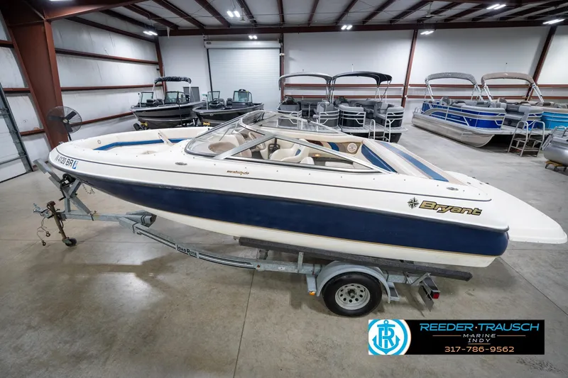 The Image of 2000 Bryant 196 Limited boat on trailer in indoor showroom with other boats. - 1