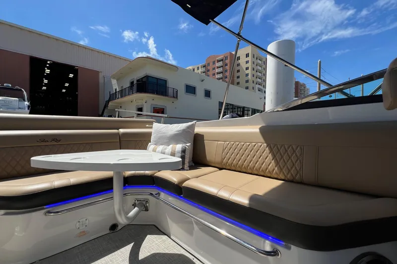 Slide: The Image of 2020 Sea Ray 280 SLX boat interior with beige seating and table, docked near buildings. - 10