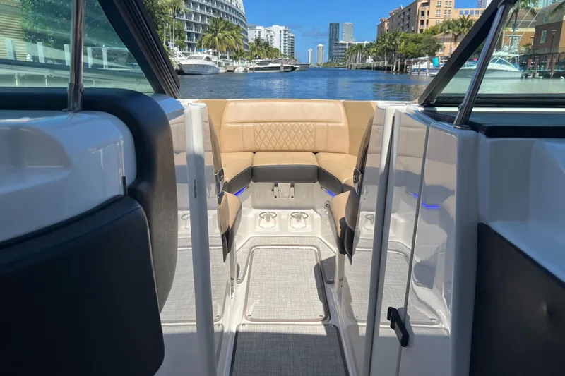 Slide: The Image of 2020 Sea Ray 280 SLX boat interior with tan seating, docked in a scenic marina. - 31