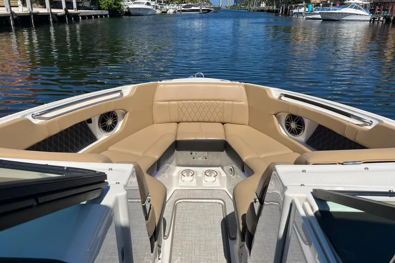 Slide: The Image of 2020 Sea Ray 280 SLX boat interior with tan seating, docked on a calm waterway. - 32
