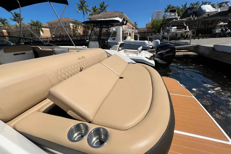 Slide: The Image of 2020 Sea Ray 280 SLX boat with tan seating, docked near palm trees and buildings. - 4