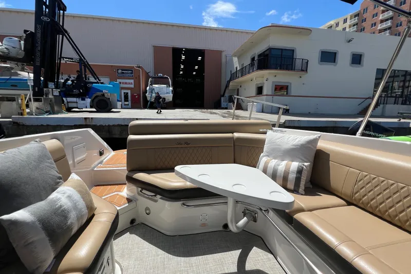 Slide: The Image of 2020 Sea Ray 280 SLX boat interior with beige seating and table at a marina. - 9