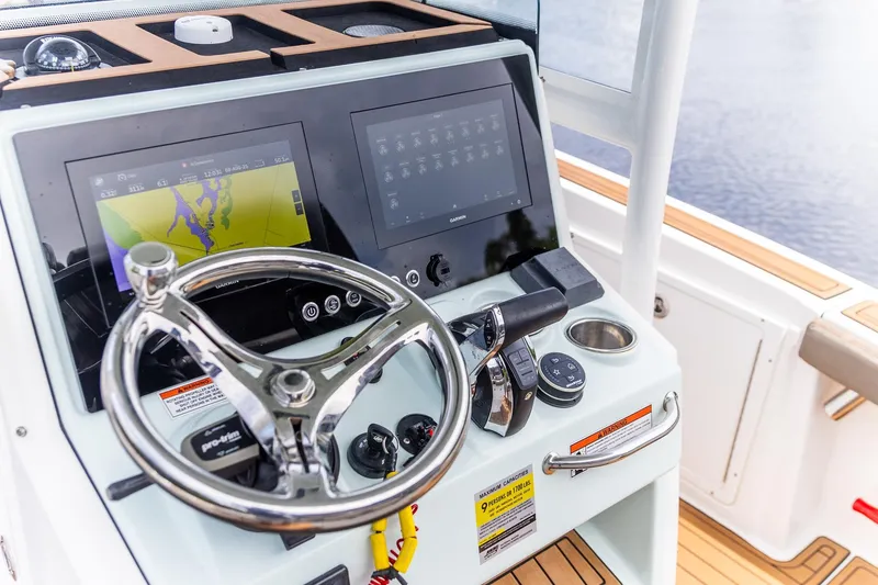 Slide: The Image of Crevalle 26 HBW 2022 boat dashboard with steering wheel and navigation screens. - 16